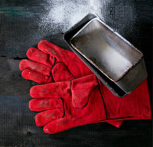 Red leather oven mitt glove pair beside metal bakeware